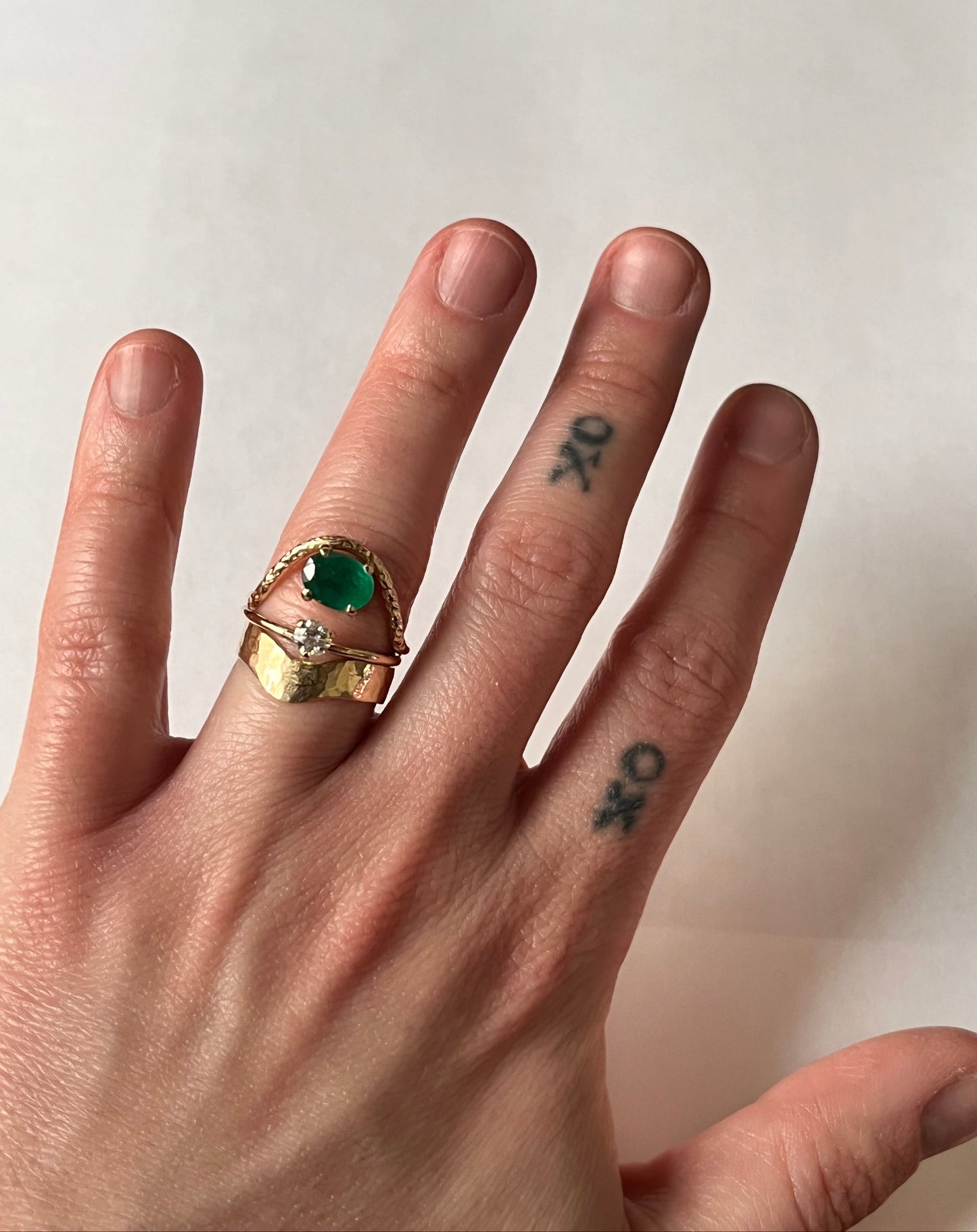 Eve Ring stacked with wide hammered gold band and green onyx rope ring on ring finger — layered gold ring styling on tattooed hand